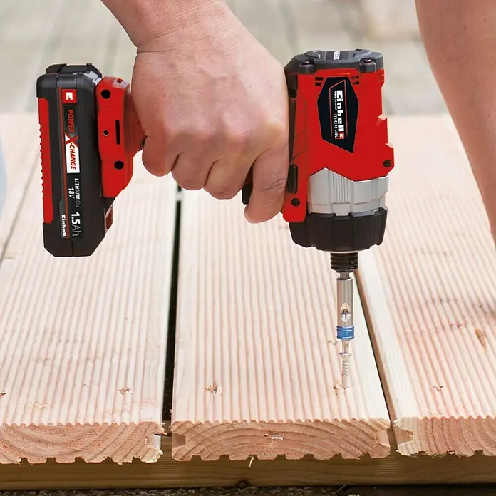 Einhell PXC 18V Atornillador de impacto de batería TE-CI 18 Li Brushless-Solo - 18 V, Sin batería, 180 Nm - Se está utilizando un atornillador de impacto inalámbrico Einhell rojo para atornillar tornillos en una cubierta de madera.