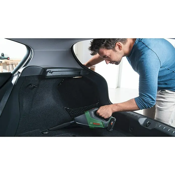 Bosch Power for All 18V Akku-Handstaubsauger UniversalVac 18 - 18 V, 1 Akku, 2,5 Ah, Behältervolumen: 0,5 l - Mann reinigt Kofferraum mit Akku-Handsauger. Der Bosch Akku-Handsauger ist ein praktisches Gerät für die schnelle Reinigung.
