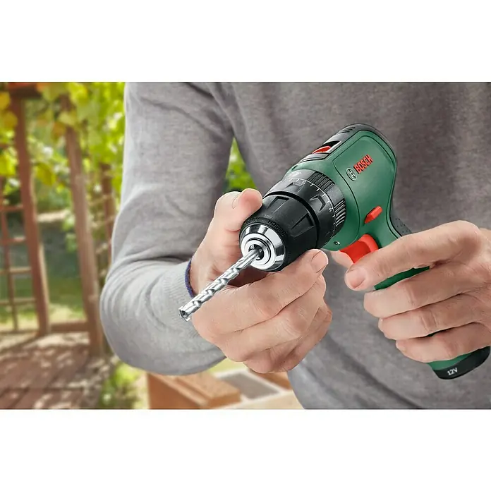 Bosch Power for All 12V Akku-Schlagbohrschrauber EasyImpact 1200 - 12 V, 2 Akkus, 1,5 Ah, 30 Nm - Nahaufnahme einer Person, die einen grünen Bosch Akku-Bohrschrauber mit eingesetztem Bohrer hält, ideal für Heimwerkerprojekte.