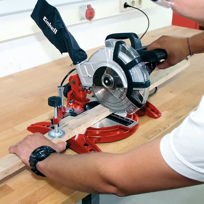 Einhell Sierra ingletadora TC-MS 2112 - 1.600 W, Diámetro hoja de sierra: 210 mm, Número de revoluciones de marcha en vacío: 5.000 r.p.m. - Primer plano de una sierra ingletadora Einhell en acción, cortando con precisión una pieza de madera. Ideal para bricolaje y uso profesional.