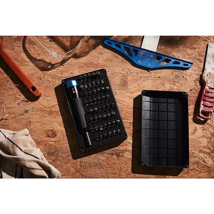 iFixit Bit-Set Manta Precision - Geeignet für: Smartphones - Das Bild zeigt ein iFixit-Werkzeugset mit verschiedenen Bits und einem Schraubendreher auf einer Holzoberfläche, umgeben von weiterem Werkzeug.