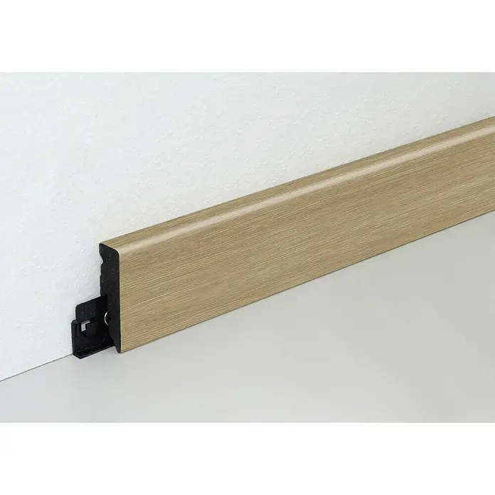 Profiles and more Sockelleiste KU051L Ashton Eiche - Ashton Eiche, 240 cm x 15 mm x 50 mm - Nahaufnahme einer Sockelleiste aus hellem Holz mit Clip-Befestigung an einer weißen Wand, ideal für moderne Bodenabschlüsse.
