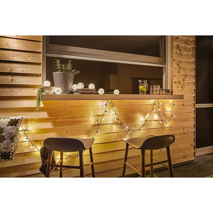 Paulmann Guirnalda luminosa LED Lampion - 3,6 m, Para exterior - Primer plano de una barra exterior con dos taburetes, adornada con luces cálidas y una fila de luces de bola.