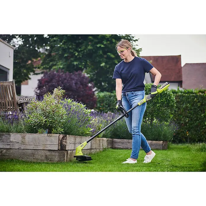 Ryobi Akku-Rasentrimmer RY36LT33A-120 - 36 V, 2 Ah, Li-Ionen, 1 Akku - Frau nutzt einen gelben Rasentrimmer der Marke Ryobi im Garten, um das Gras zu trimmen. Gartengeräte für die Rasenpflege.