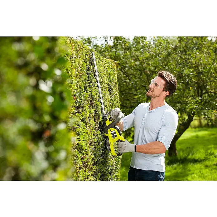 Ryobi ONE+ Akku-Heckenschere RHT184520 - 18 V, Li-Ionen, 1 Akku, Schnittlänge: 45 cm - Mann schneidet eine Hecke mit einer RYOBI Akku-Heckenschere, Schutzbrille und Handschuhen. RYOBI Gartengeräte für den perfekten Heckenschnitt.