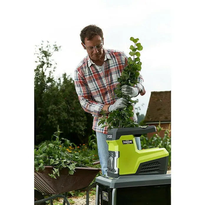 Ryobi Elektro-Leisehäcksler RSH3045U - Max. Aststärke: 4,5 cm, 3.000 W - Mann benutzt einen Ryobi 3000W Häcksler im Garten. Der Häcksler zerkleinert Äste und Grünabfälle für die Kompostierung.