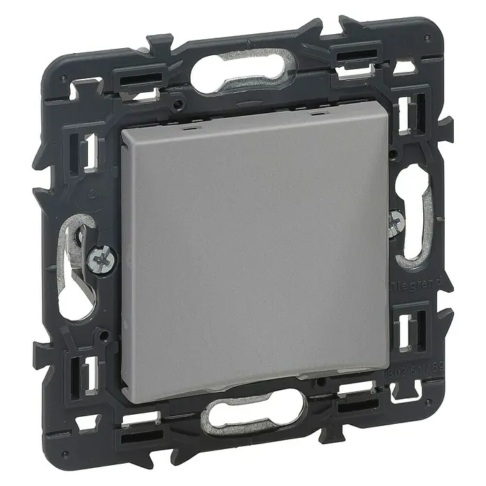 Legrand Valena Next Pasacables - Aluminio, Diámetro: 12 mm - Primer plano de un interruptor de luz Legrand en gris, enmarcado en un marco oscuro. El interruptor tiene un diseño cuadrado y moderno.