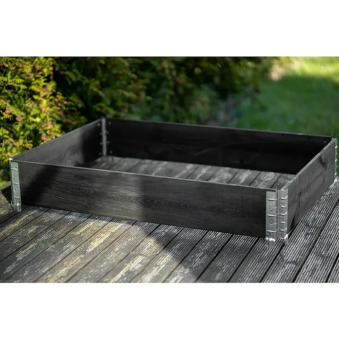 Gardol Hochbeetumrandung Palettenrahmen - L x B x H: 120 x 80 x 20 cm, Holz, Schwarz - Ein dunkles, rechteckiges Hochbeet aus Holz mit metallenen Eckverbindungen steht auf einem Holzdeck.