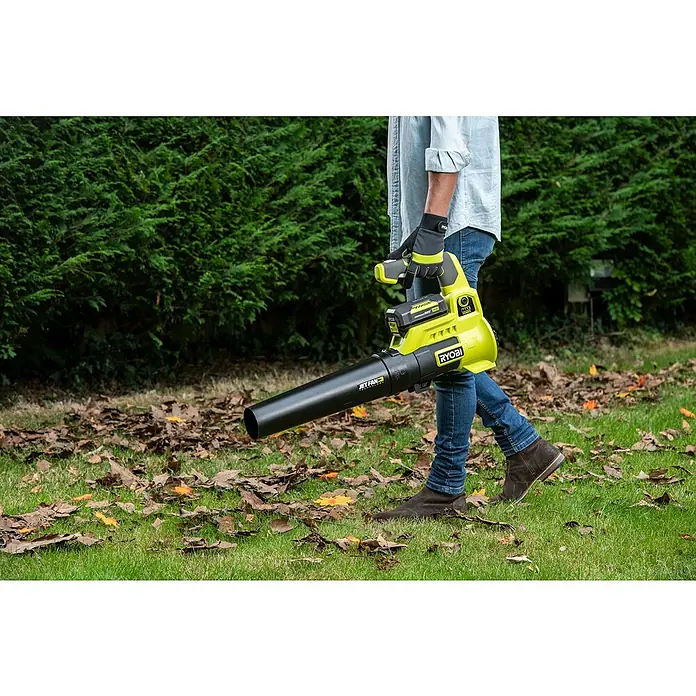 Ryobi Akku-Laubbläser RY36BLA-0 - 36 V, Ohne Akku, Blasgeschwindigkeit: 152 km/h, Blasleistung: 14,86 m³/min - Nahaufnahme eines Mannes, der einen gelben Ryobi-Laubbläser auf einem Rasen mit Herbstlaub verwendet.