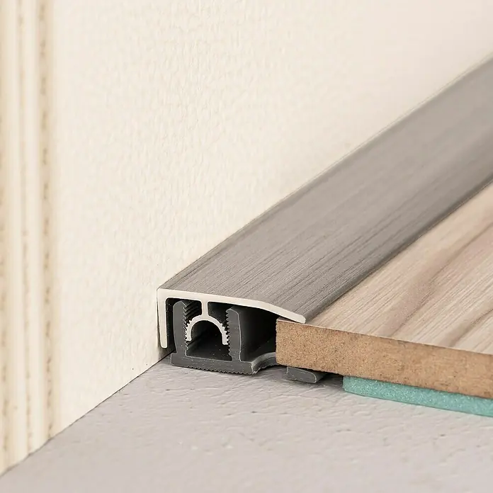 LOGOCLIC Abschlussprofil 313 - Aluminium gebürstet, 0,9 m x 26 mm, Montageart: Stecken - Das Bild zeigt ein Übergangsprofil aus Aluminium, das zwischen Wand und neu verlegtem Laminatboden angebracht wurde.