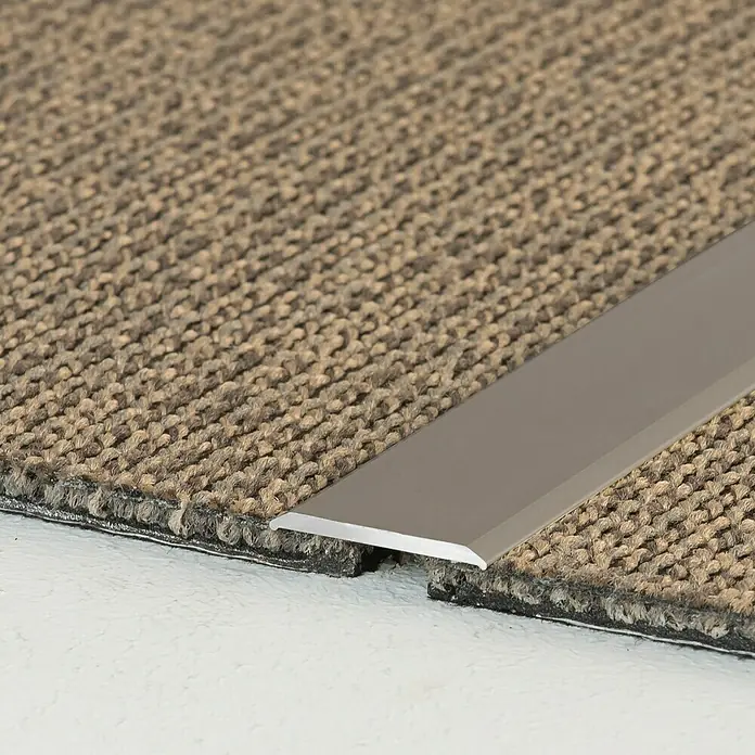 LOGOCLIC Übergangsprofil 114 - Edelstahl matt, 1 m x 24 mm x 2 mm, Montageart: Kleben - Detailaufnahme einer silbernen Übergangsleiste zwischen zwei Teppichfliesen. Ideal für saubere und ästhetische Bodenabschlüsse.