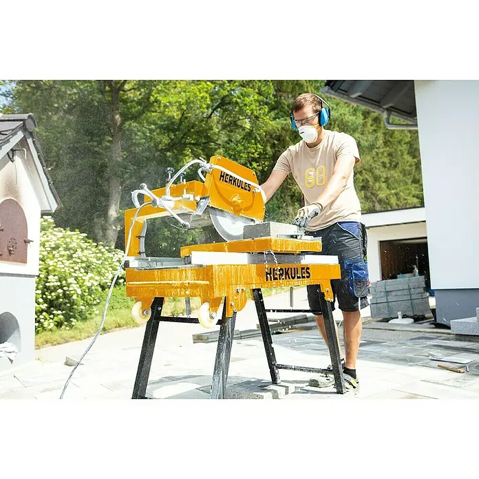 Herkules Steintrennmaschine HFS 3500 Pro - 2.000 W, Durchmesser Scheibe: 350 mm, Schnitthöhe: 72 mm - 110 mm - Der Mann benutzt eine Herkules Steinsäge, um Steine zuzuschneiden, mit Schutzausrüstung für Augen und Ohren.