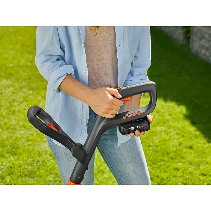Gardena Power for All 18V Akku-Rasentrimmer ComfortCut - 18 V, Li-Ionen, Ohne Akku, Schnittbreite Messer: 23 cm - Nahaufnahme einer Person, die einen Gardena Akku-Rasentrimmer mit einem 2,0-Ah-Akku hält, ideal für präzise Rasenpflege.