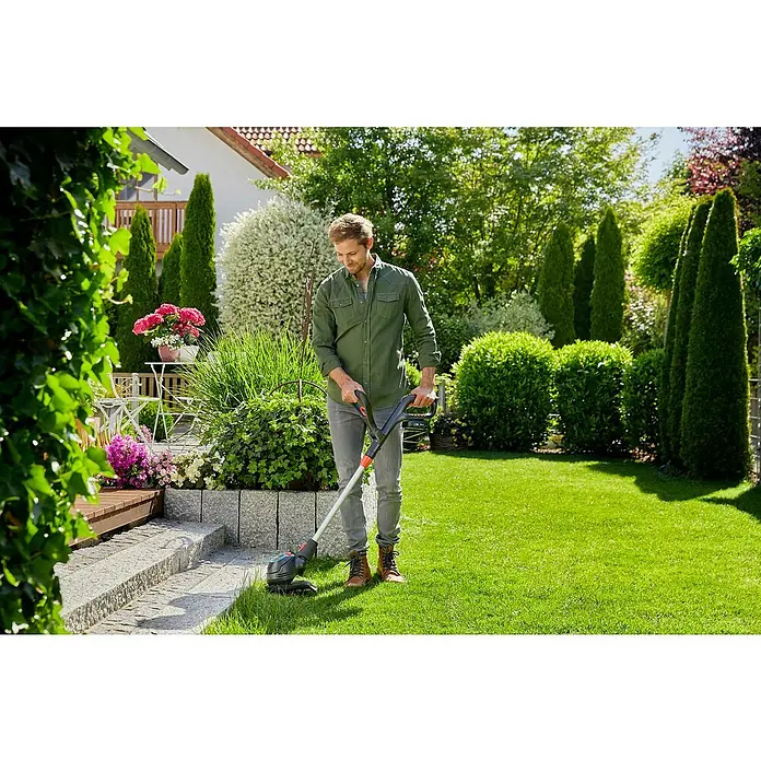 Gardena Power for All 18V Akku-Rasentrimmer ComfortCut - 18 V, Li-Ionen, Ohne Akku, Schnittbreite Messer: 23 cm - Ein Mann benutzt einen Gardena Akku-Rasentrimmer in seinem Garten, um die Rasenkanten zu schneiden. Perfekt für präzise Gartenarbeit.