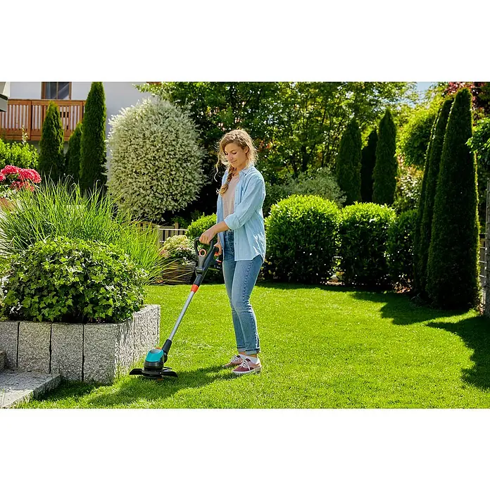 Gardena Power for All 18V Akku-Rasentrimmer EasyCut - 18 V, Li-Ionen, Ohne Akku, Schnittbreite Messer: 23 cm - Frau bedient einen Rasentrimmer der Marke Gardena in einem gepflegten Garten. Das Gerät erleichtert die Gartenarbeit.