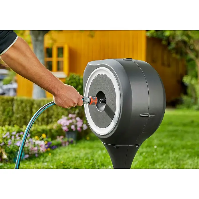 Gardena Schlauchbox RollUp S - Schlauchlänge: 15 m - Ein Mann schließt einen Gartenschlauch an eine GARDENA Schlauchbox an. Praktische Bewässerungslösung für Gärten und Außenbereiche.