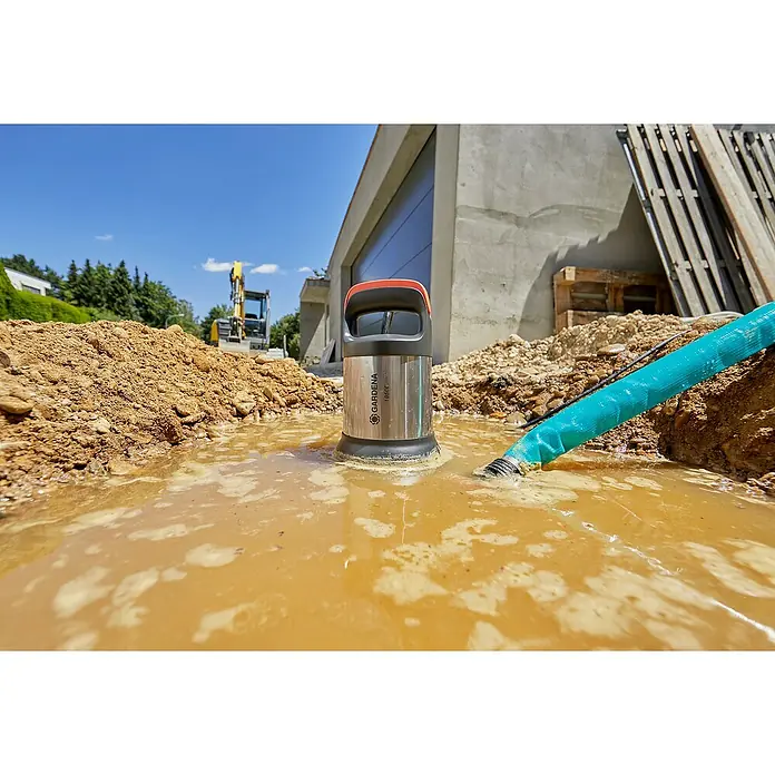 Gardena Schmutzwasserpumpe 19500 Aquasensor - 860 W, Max. Fördermenge: 19.500 l/h - Nahaufnahme der GARDENA 18500 inox Schmutzwasserpumpe im Einsatz, umgeben von schmutzigem Wasser und Baustellenmaterialien.