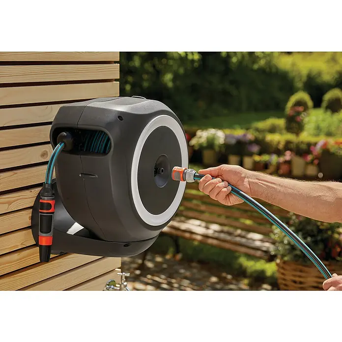 Gardena Wand-Schlauchbox RollUp S - Schlauchlänge: 15 m - Eine graue Gardena Wand-Schlauchbox 35 roll-up automatic mit Schlauch und Arm, montiert an einer Holzwand im Garten.