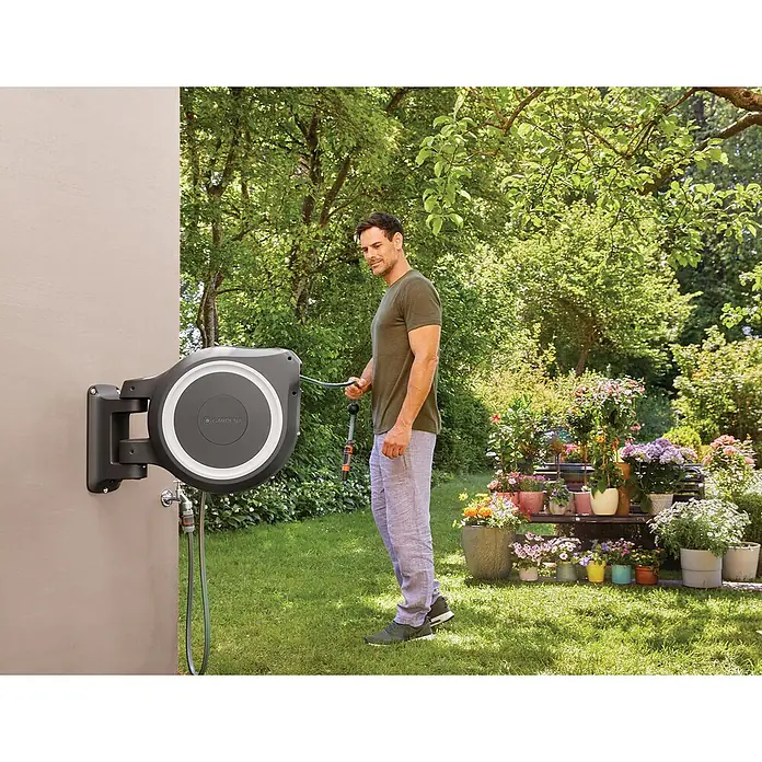 Gardena Wand-Schlauchbox RollUp M/L - Schlauchlänge: 25 m - Ein Mann benutzt eine Gardena Schlauchbox zur Bewässerung seines Gartens. Praktische Schlauchaufbewahrung mit komfortabler Bedienung.