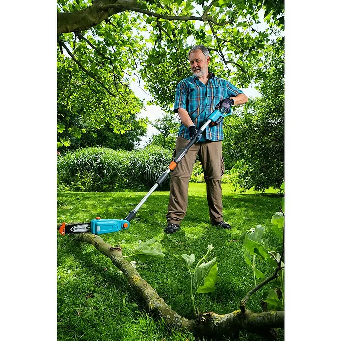 Gardena Power for All 18V Akku-Hochentaster - 18 V, 1 Akku, Schwertlänge: 20 cm - Ein Mann benutzt eine Gardena Akku-Astschere TCS 20/18V P4A, um einen Baumstamm im Garten zu schneiden.