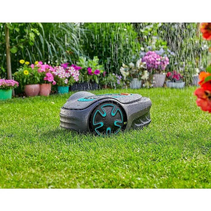 Gardena Mähroboter Sileno minimo 500 - 500 m², Schnittbreite: 16 cm, Induktionsgestützte Navigation, Begrenzungskabel - Gardena Mähroboter auf einem Rasen unter Regentropfen. Der Rasenmäher ist grau mit türkisfarbenen Akzenten. Blumen im Hintergrund.