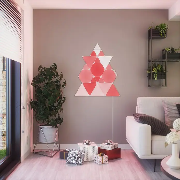 Nanoleaf Erweiterungskit Shapes Triangles 3 Panels - Weiß, RGBW, Triangles, Smart Home-fähig: Ja - Festliche Szene mit Nanoleaf-Lichtern in Weihnachtsbaumform, Geschenken und Sofa, die eine gemütliche und moderne Weihnachtsatmosphäre schaffen.