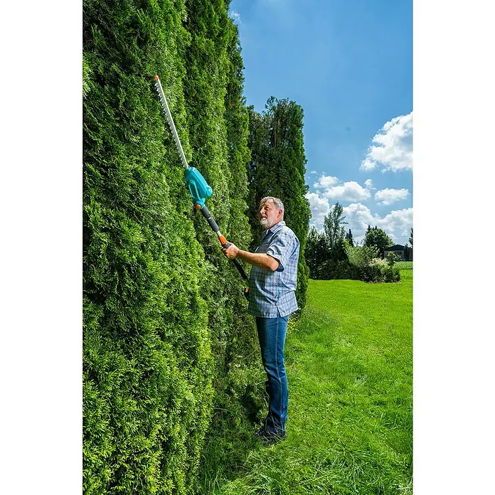 Gardena Power for All 18V Teleskop-Heckenschere - 18 V, Ohne Akku, Schwertlänge: 42 cm - Ein Mann schneidet eine hohe Hecke mit einer Gardena Akku-Teleskop-Heckenschere, wobei er Wert auf präzise Ergebnisse legt.