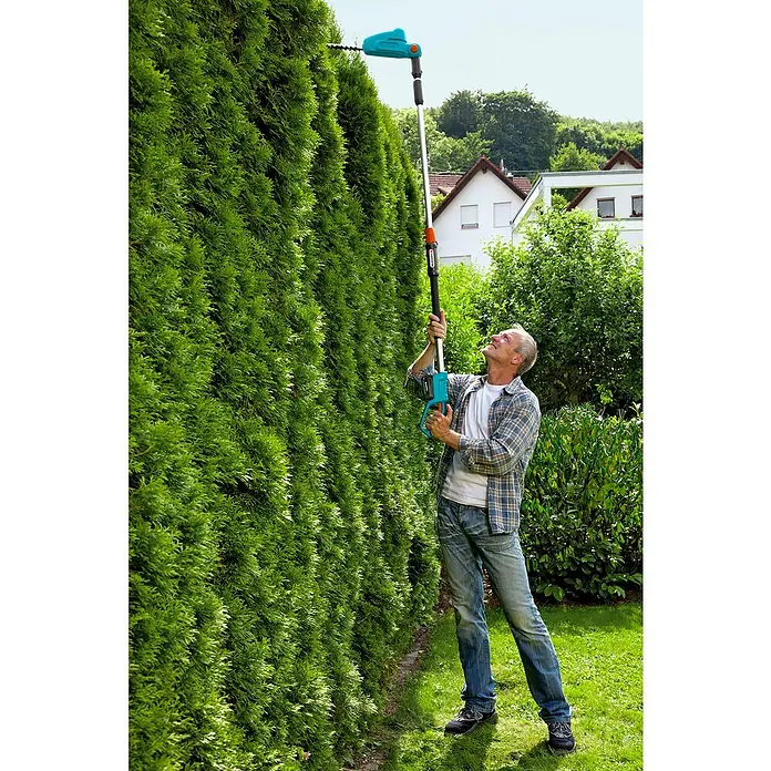 Gardena Power for All 18V Teleskop-Heckenschere - 18 V, Ohne Akku, Schwertlänge: 42 cm - Ein Mann beschneidet eine hohe Hecke mit einer Gardena Akku-Teleskop-Heckenschere, um den Garten in Form zu bringen.