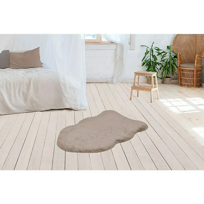 Kunstfell Happy - Taupe, 90 x 60 cm, 100 % Polyester (Flor) - Flauschiger Teppich in Form einer Wolke in einem hellen Raum mit Holzboden, der eine gemütliche und stilvolle Atmosphäre erzeugt.