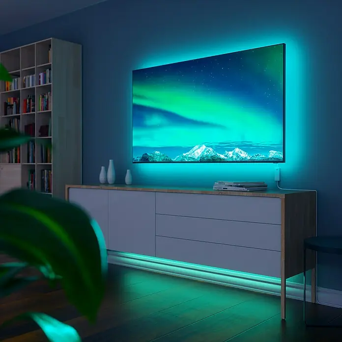 Nanoleaf Smart-LED-Band Essentials Lightstrip Starterkit - 23 W, Weiß, Länge: 2 m, RGBW - Das Bild zeigt einen Fernseher mit LED-Hintergrundbeleuchtung in einem modernen Wohnzimmer, die eine entspannende Atmosphäre schafft.