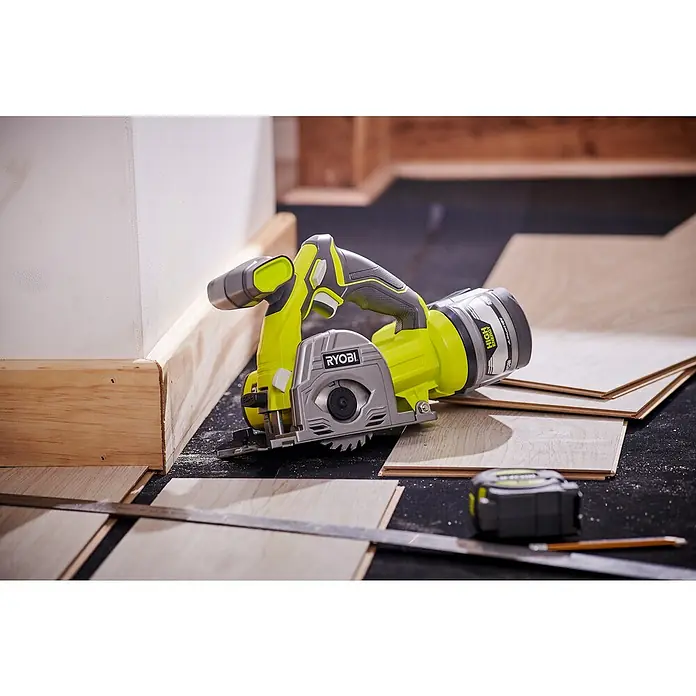 Ryobi ONE+ Maschinenpaket - Akku-Tauchsäge R18MMS-0 + gratis Starter-Kit - Ryobi Akku-Handkreissäge auf Holzplatten. Das Werkzeug ist grün und grau, daneben liegen ein Maßband, ein Bleistift und ein Winkel.