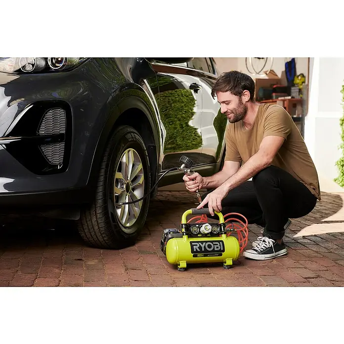 Ryobi ONE+ Maschinenpaket - Akku-Kompressor PRO + gratis Starter-Kit - Ein Mann befüllt einen Reifen eines Autos mit einem gelben Ryobi Luftkompressor.