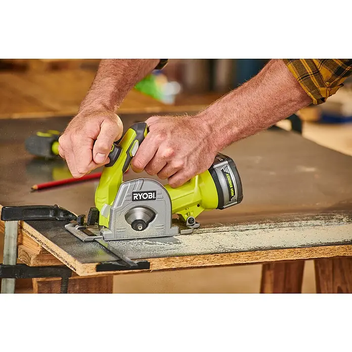 Ryobi ONE+ Maschinenpaket - Akku-Tauchsäge R18MMS-0 + gratis Starter-Kit - Ein Mann benutzt eine Ryobi Akku-Handkreissäge, um ein Stück Holz zu schneiden, wobei der Fokus auf der grünen und grauen Säge liegt.