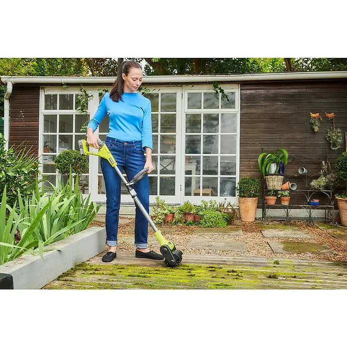 Ryobi ONE+ Oberflächenreiniger RY18PCB-0 - Akkubetrieben, 18 V, Ohne Akku - Frau benutzt einen gelb-grauen Ryobi-Bürstenentferner im Garten, um Moos zu entfernen.
