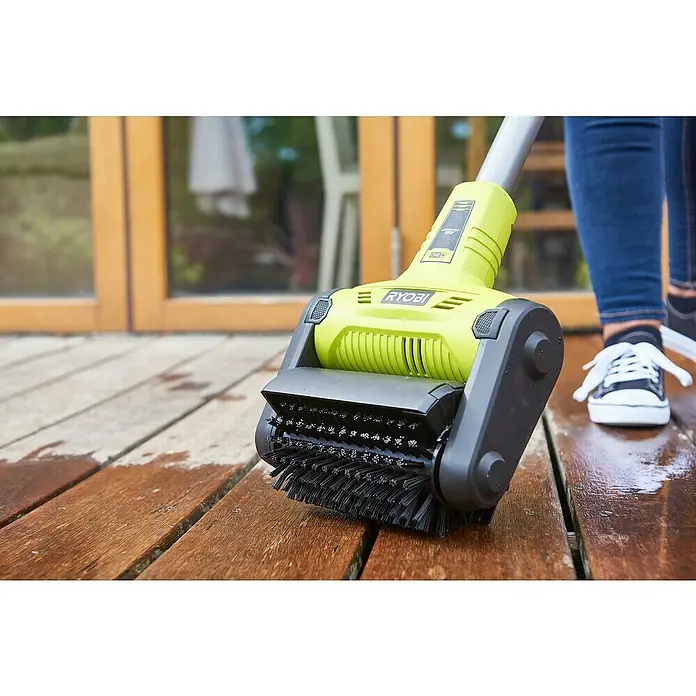 Ryobi ONE+ Oberflächenreiniger RY18PCB-0 - Akkubetrieben, 18 V, Ohne Akku - Nahaufnahme eines RYOBI-Terrassenreinigers in Aktion, der Schmutz mit einer Bürste entfernt.