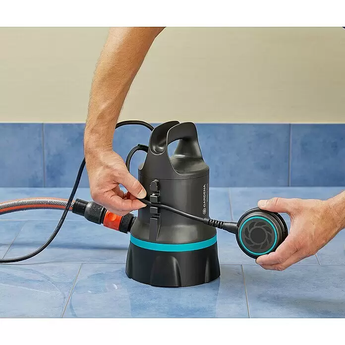 Gardena Klarwassertauchpumpe 9000 - 300 W, Max. Fördermenge: 9.000 l/h - Person verbindet Kabel mit schwarzer Gardena Tauchpumpe mit türkisfarbenem Band und hält Schwimmerschalter. Ein Schlauch ist angeschlossen.