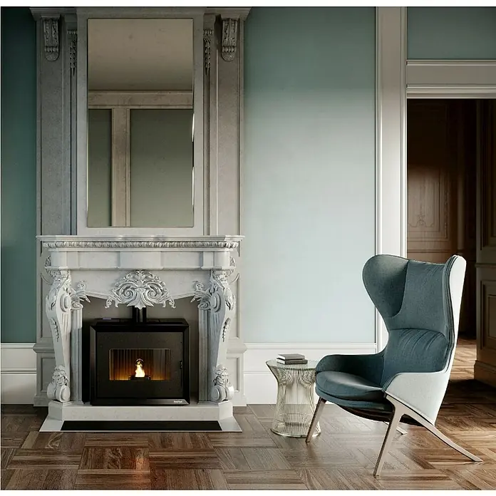 FreePoint Pelletofen Modo Airtight - 9,36 kW, Raumheizvermögen: 225 m³, 0,59 kg/h - 2,18 kg/h, Schwarz - Elegantes Interieur mit einem modernen Kaminofen, der in einem kunstvollen Marmorkamin integriert ist, neben einem stilvollen Sessel.