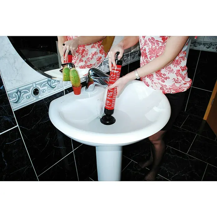 Rothenberger Industrial Abflusspumpe ROPUMP - Geeignet für: Abflüsse - Eine Frau benutzt eine Rothenberger Rohrreinigungspumpe in einem Waschbecken, um eine Verstopfung zu lösen. Die Pumpe ist rot und schwarz.