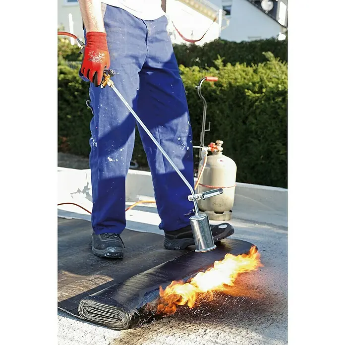 Rothenberger Industrial Polygas-Anwärmbrenner-Set MONO - 30 kW, Durchmesser Brenner: 57 mm - Ein Dachdecker verschweißt Dachpappe mit einem Brenner, um eine wasserdichte Abdichtung zu gewährleisten, während Flammen lodern.