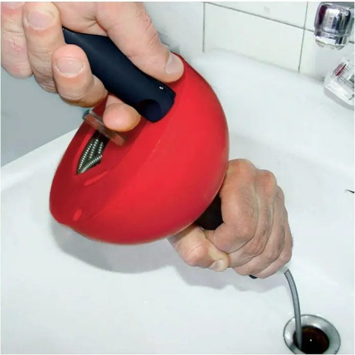 Rothenberger Industrial Rohrreinigungsspirale Rohr-Perfekt - Spiralenlänge: 4,5 m, Geeignet für: Abflüsse - Rohrreinigungsschnecke mit rotem Gehäuse und schwarzem Griff wird verwendet, um einen Abfluss zu reinigen. Das Gerät wird von einer Hand gehalten.