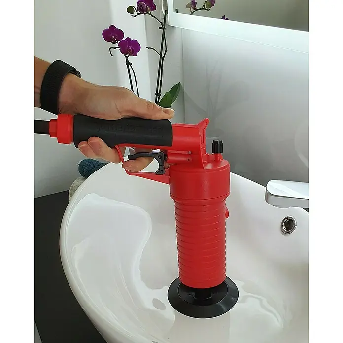 Rothenberger Industrial Pressluft-Rohrreiniger - 4 bar, 5 -tlg. - Eine Hand bedient eine rote Abfluss-Pömpel-Pistole auf einem Waschbecken. Effektives Werkzeug zur Rohrreinigung für den Haushalt.