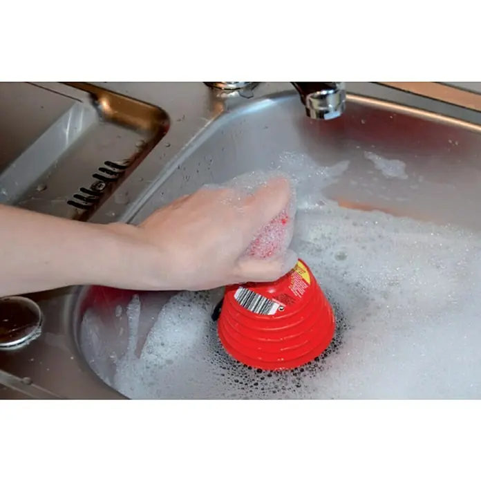 Rothenberger Industrial Mini-Saugglocke - Durchmesser: 116 mm, Geeignet für: Abflüsse - Ein roter Spülbürsten-Spender mit Seife wird in einer Spüle mit schaumigem Wasser gereinigt, wobei die Hand der Person den Schwamm hält.