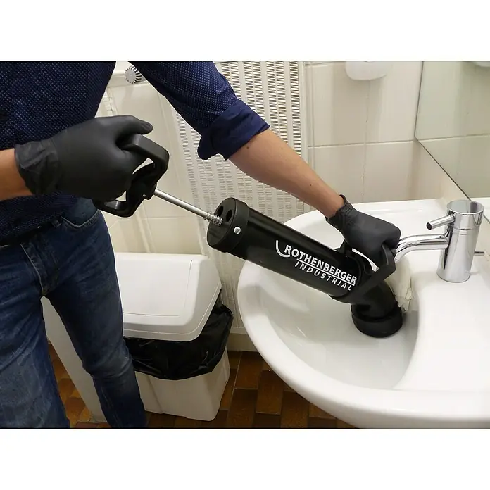 Rothenberger Industrial Abflusspumpe RoPump - Geeignet für: Abflüsse - Ein Handwerker benutzt eine Rothenberger Industrial Rohrreinigungsgerät um einen verstopften Abfluss in einem Waschbecken zu reinigen.