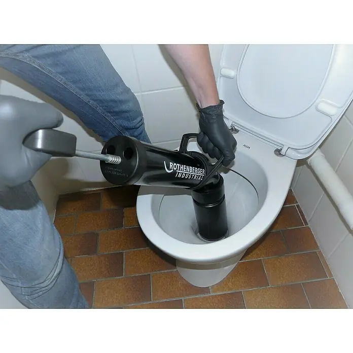 Rothenberger Industrial Abflusspumpe RoPump - Geeignet für: Abflüsse - Eine Rothenberger Industrial Rohrreinigungsgerät wird in einer Toilette verwendet, um Verstopfungen zu beseitigen. Sanitärwerkzeug im Einsatz.
