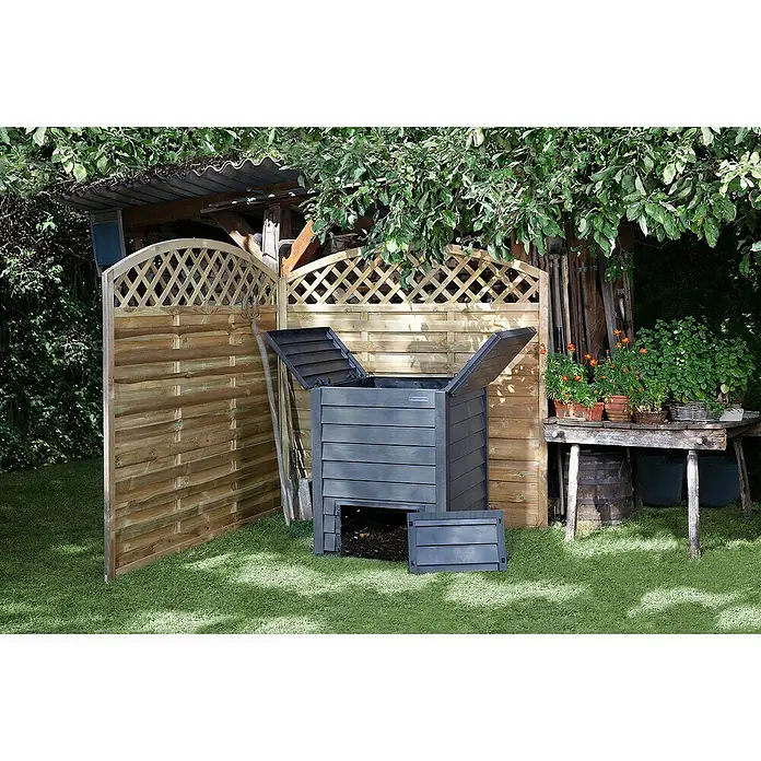 Garantia Komposter Thermo-Wood - 400 l, 72 x 72 x 90 cm, Mit Bodengitter - Ein grauer Thermokomposter mit geöffnetem Deckel und einer Klappe zum Entnehmen des Komposts. Der Komposter steht im Garten vor einem Holzzaun.