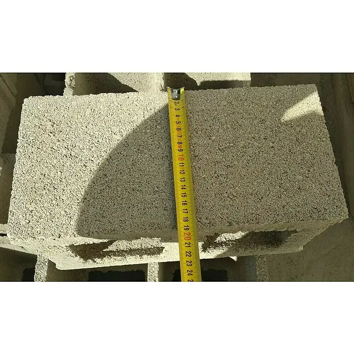 BHS Valencia Bloque de hormigón poroso - 39 x 19 x 19 cm, Hormigón - Primer plano de un bloque de hormigón gris con una cinta métrica que muestra su longitud de unos 20 cm.