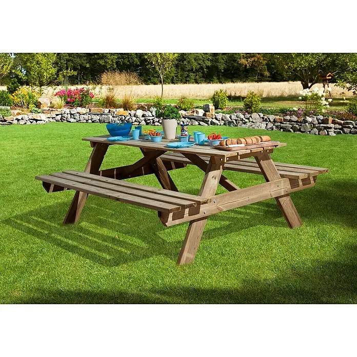 Weka Picknicktisch 662 - 3 -tlg., Nadelholz, Natur - Eine rustikale Picknickbank aus Holz auf einer grünen Wiese, gedeckt mit blauem Geschirr und Speisen für ein entspanntes Essen im Freien.