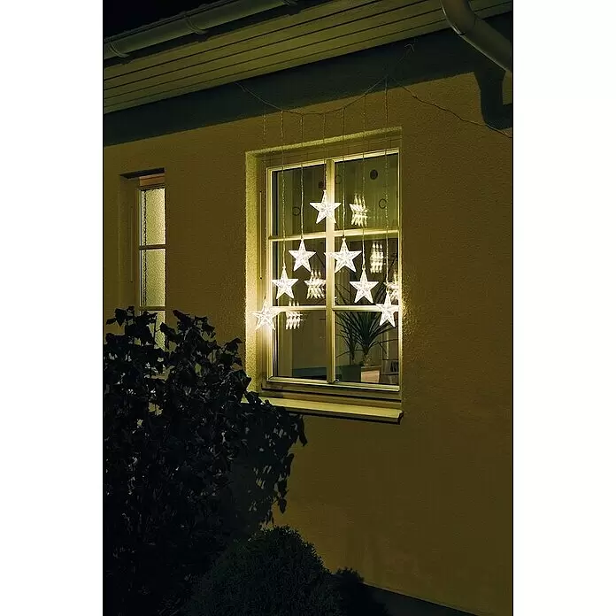 Konstsmide LED-Lichtervorhang - Außen, 5,762 m, Warmweiß, Netzbetrieben - Warmweiße LED-Lichterkette mit Sternen, nachts als festliche Dekoration in einem Fenster hängend.