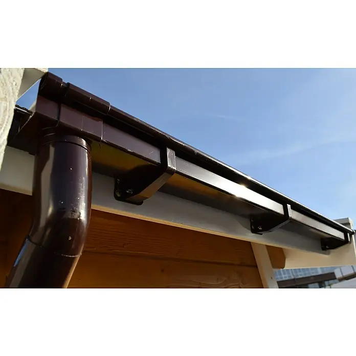 Weka Dachrinnen-Set - Passend für: Flach- & Pultdächer bis Dachbreite 400 cm, Braun - Nahaufnahme einer braunen Dachrinne und eines Fallrohrs an einem Gebäude unter einem blauen Himmel. Eine Dachrinne schützt ein Haus vor Wasserschäden.