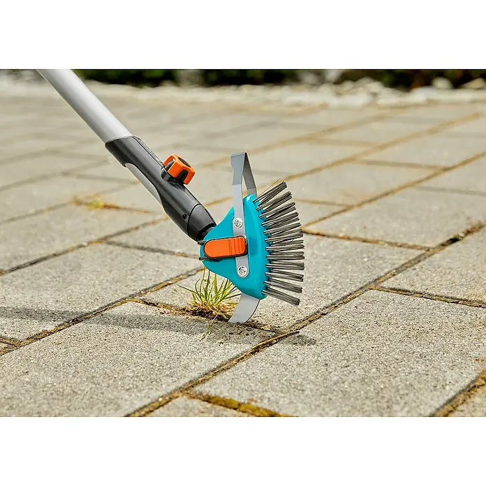 Gardena Combisystem Fugenkratzer 3in1 - Länge: 23,5 cm, Material Gerätekopf: Edelstahl - Bild einer Fugenbürste mit Teleskopstiel beim Entfernen von Unkraut zwischen Pflastersteinen.